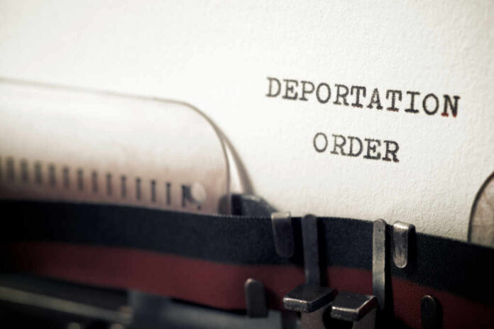 Close-up of a typewriter with a paper showing the words DEPORTATION ORDER