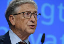 DOJ Files Expose Billionaire’s Shocking Epstein Connections A man in a suit speaking at a conference with a microphone