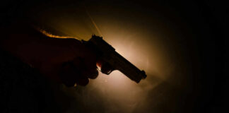 Silhouette of a hand holding a handgun against a dramatic light background