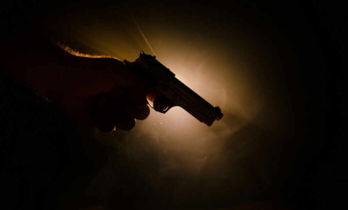 Silhouette of a hand holding a handgun against a dramatic light background