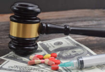 A gavel placed on top of money with pills and a syringe nearby