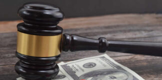 A gavel placed on top of money with pills and a syringe nearby