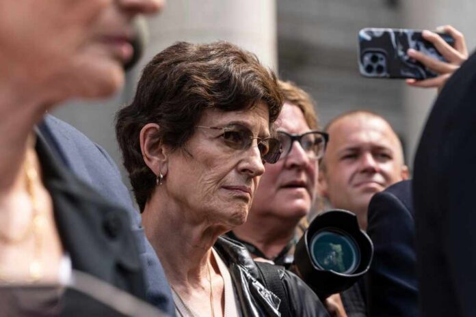 A group of people at an outdoor event with one woman in focus showing a serious expression