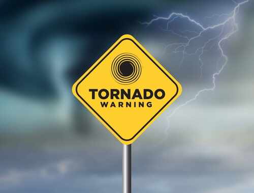 A yellow tornado warning sign against a stormy background