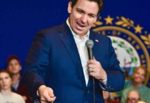 A man in a blue suit speaking into a microphone at a public event