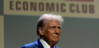 A man in a suit speaking at a podium during a conference