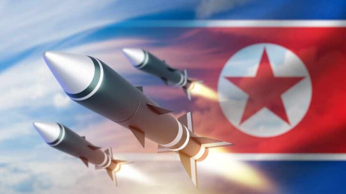 shutterstock_2552552771.jpg Three missiles launching against a backdrop of the North Korean flag