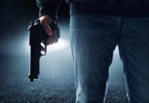 A person holding a handgun in a dark environment