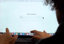 Person interacting with a computer screen displaying a chatbot interface