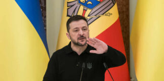 Ukrainian leader speaking at a podium with national flags in the background
