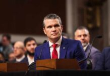 Individual in formal attire seated at a senate hearing