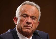 Close-up of a serious-looking man speaking into a microphone