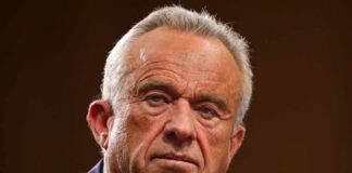 Close-up of a serious-looking man speaking into a microphone