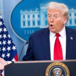 A man speaking at a podium during a press conference at the White House