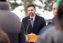Man in formal attire speaking at a podium during a winter event