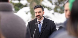 Man in formal attire speaking at a podium during a winter event