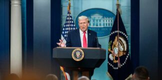 A man speaking at a podium during a press conference at the White House