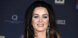 A woman with long hair and glamorous makeup smiling at a red carpet event