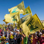 Large crowd waving yellow flags at a political rally