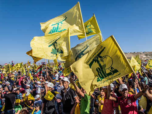 Large crowd waving yellow flags at a political rally