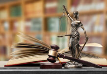 A gavel and a statue of Lady Justice beside an open law book
