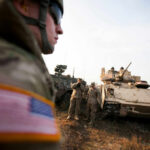 Soldiers in military gear coordinating near armored vehicles during training