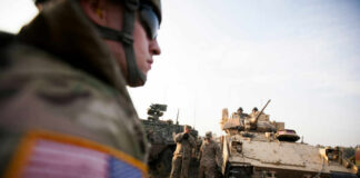 Soldiers in military gear coordinating near armored vehicles during training