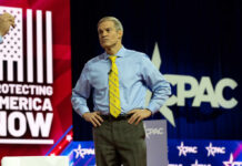 Political CHAOS Shakes Supreme Court Debate A man in a blue shirt and yellow tie stands on stage at a political conference