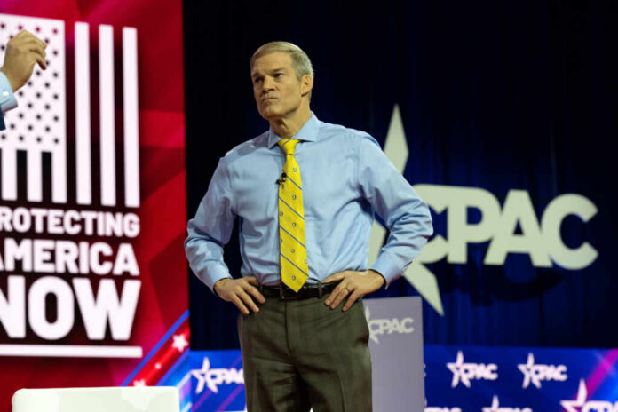 shutterstock2270811551jpg A man in a blue shirt and yellow tie stands on stage at a political conference
