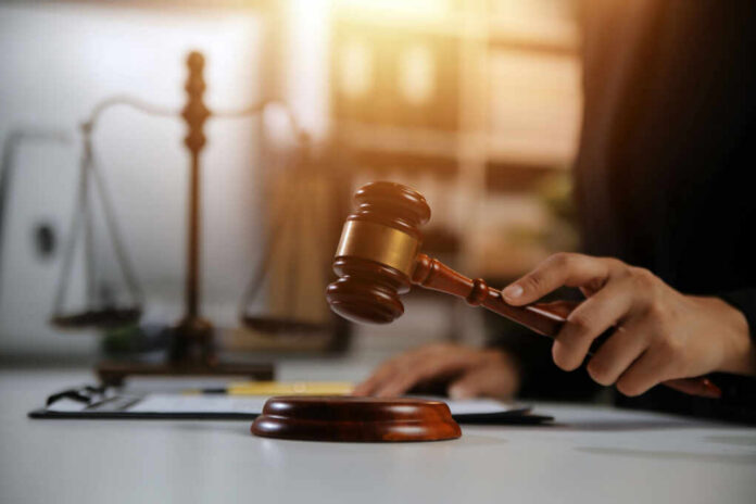 A gavel being struck on a desk in a courtroom setting