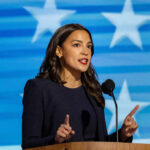 A female politician delivering a speech at a podium with a star-patterned background