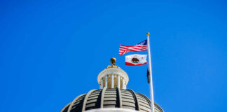 Surprising Power Grab Rocks California Primary View of a state capitol dome with American and California flags against a blue sky