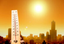 A thermometer held against a sunset city skyline