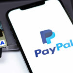 Close-up of a smartphone displaying the PayPal logo next to credit cards