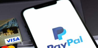 Close-up of a smartphone displaying the PayPal logo next to credit cards
