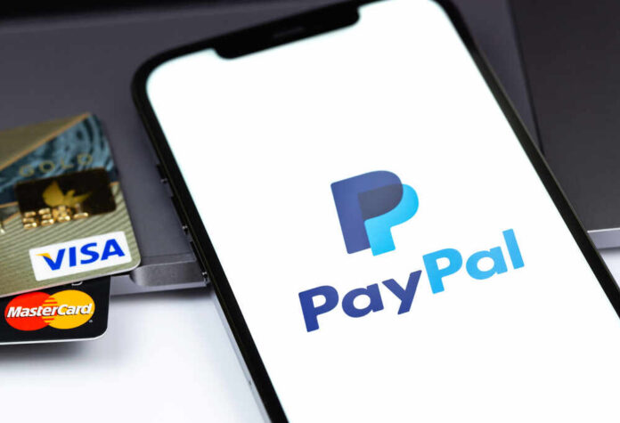 Close-up of a smartphone displaying the PayPal logo next to credit cards