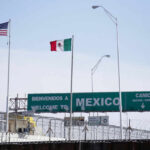 Flags of the United States and Mexico at a border crossing with a welcome sign
