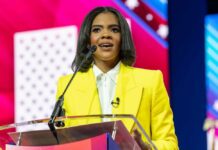 A woman in a bright yellow suit speaking at a podium during a conference