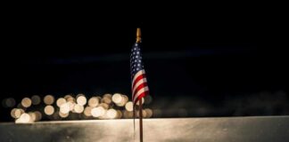 Shocking Whistleblower Testimony Exposes Alien Cover-Up A small American flag positioned in front of the word 'PENTAGON' on a reflective surface