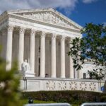 The Supreme Court building with columns and a statue in front