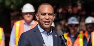 A man speaking at a podium with construction workers in the background