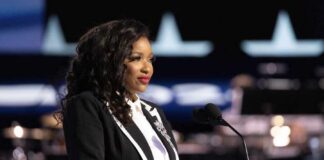 A woman in formal attire speaking at a podium with a microphone