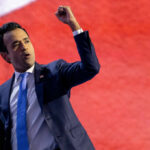 A speaker passionately delivering a speech with a raised fist