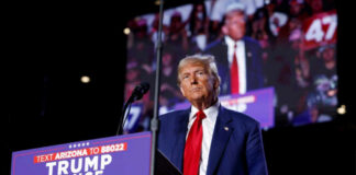 MAGA Clash: Trump’s Bold Move in Texas Runoff A man in a suit stands at a podium with a microphone during a political rally
