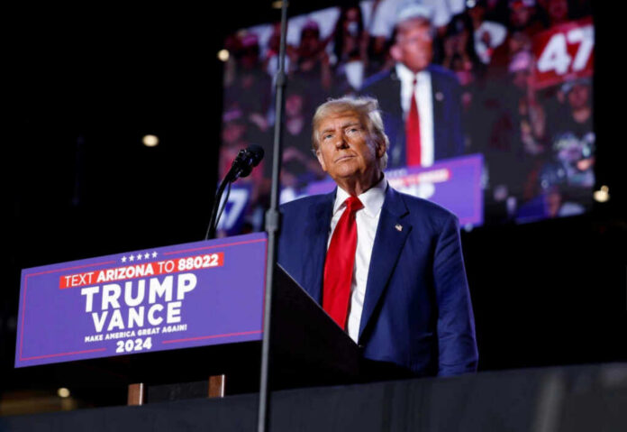 shutterstock_2541105347 A man in a suit stands at a podium with a microphone during a political rally