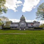 Capitol building with green dome behind a lawn and trees