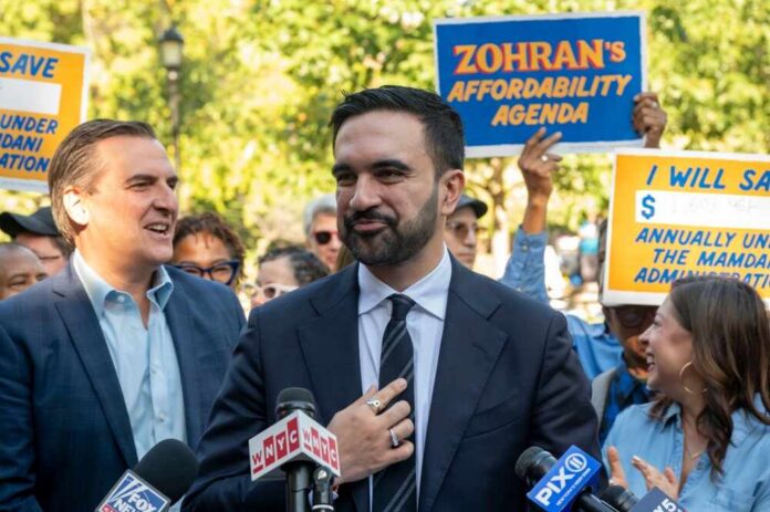 A politician speaking at a rally with supporters holding signs