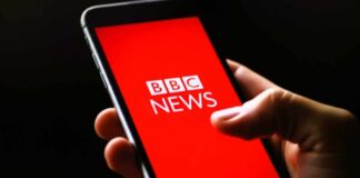 Hand holding smartphone with a red news app screen