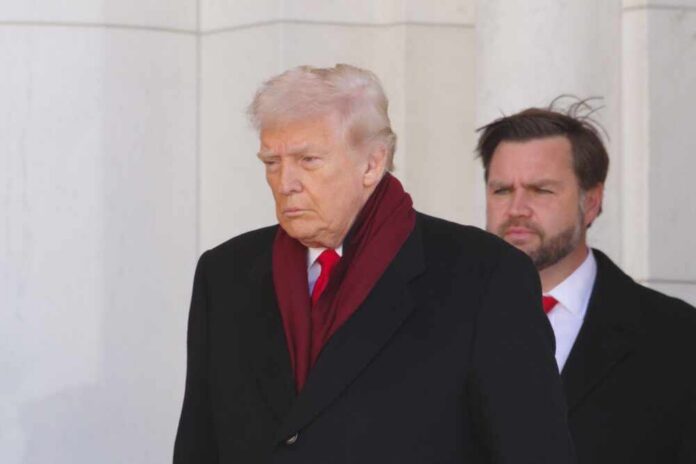 A political figure walking with a serious expression, wearing a dark coat and red scarf