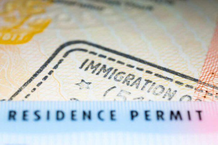 Immigration,Concept,Image.,Residence,Permit,Card,Over,Immigration,Stamp,On Close-up of a residence permit showing immigration details